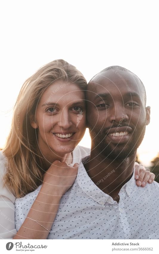 Happy diverse couple hugging on evening street bonding embrace cheerful happy in love toothy smile amorous railing lifestyle beautiful sunlight black enjoy