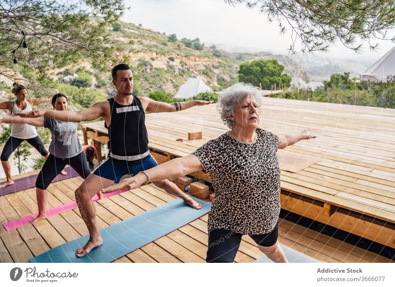 Team of active people doing Warrior II yoga asana in camp warrior ii virabhadrasana b stretch wellness healthy balance class practice wellbeing vitality zen