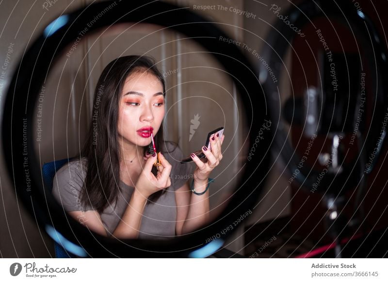 Beauty blogger applying makeup during shooting session beauty vlog woman cosmetic foundation record video young asian female ethnic camera light lamp mirror