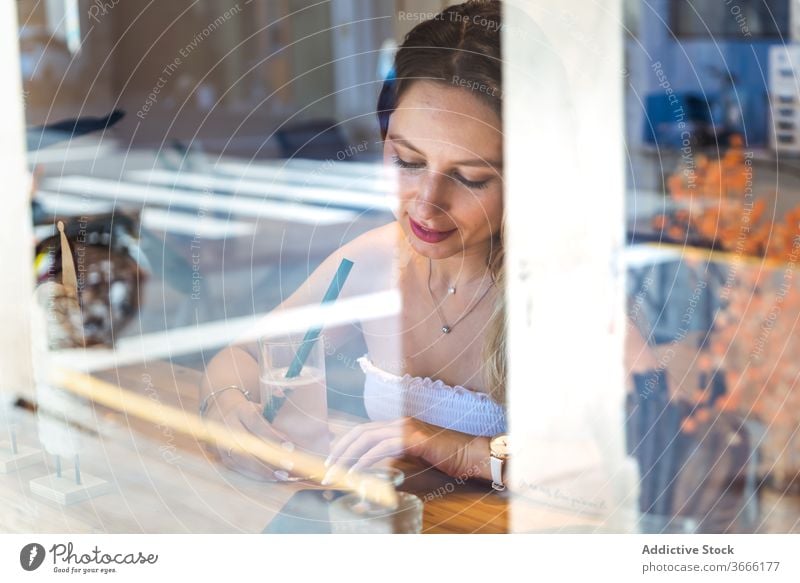 Happy young woman relaxing in cafe with glass of lemonade on sunny day drink juice fresh read smartphone using cheerful device gadget rest female casual mobile