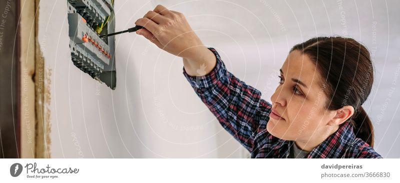 Electrician working on the distribution panel of a house woman electrical technician screwdriver electrician electrical installation inspection testing banner