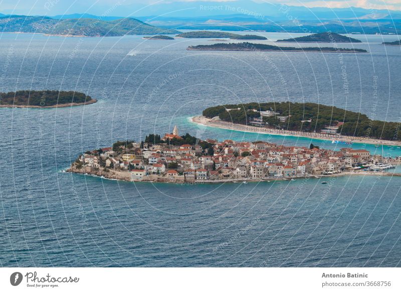 Town of Primosten peninsula seen from a nearby hill. Blue bright day, adriatic sea surrounding the small old town shore attraction picturesque village harbor