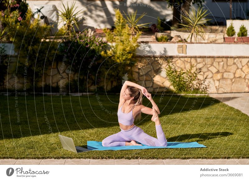 Flexible woman doing yoga in King Pigeon pose king pigeon pose practice eka pada rajakapotasana courtyard mat tranquil flexible harmony female active wear