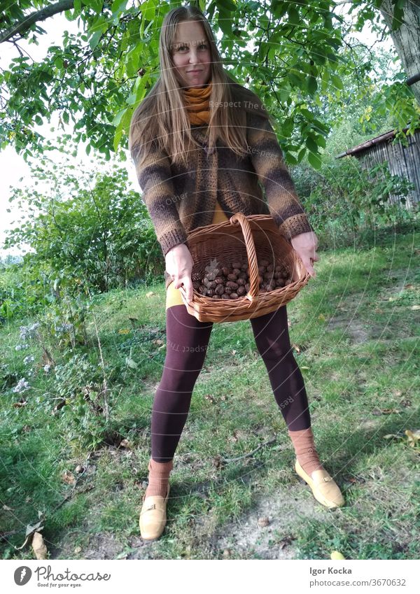 Portrait of beautiful woman holding basket with wallnuts Woman female Basket standing portrait happy smiling cheerful lifestyle Brown warm clothes casual