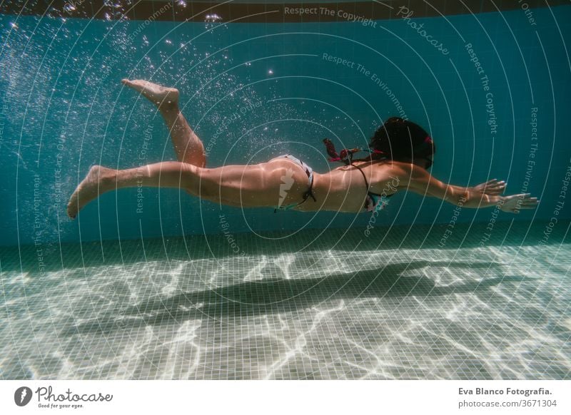 young woman diving underwater in a pool. summer and fun lifestyle sunglasses swimming bubbles caucasian dive clear health light action wet swimmer blue active