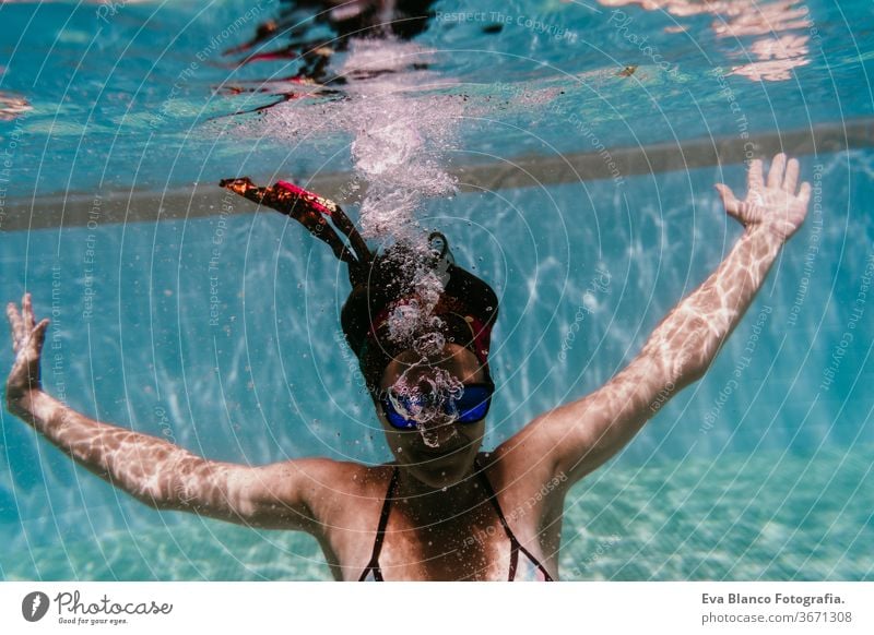 young woman diving underwater in a pool. summer and fun lifestyle sunglasses swimming bubbles caucasian dive clear health light action wet swimmer blue active