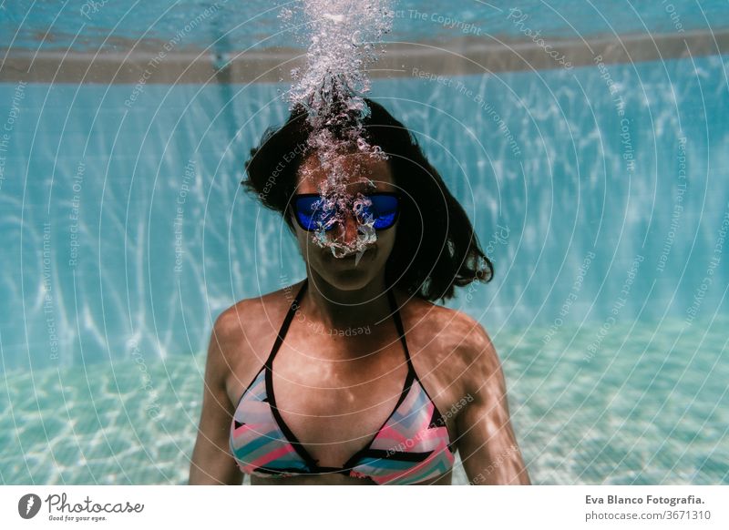 young woman diving underwater in a pool. summer and fun lifestyle sunglasses swimming bubbles caucasian dive clear health light action wet swimmer blue active