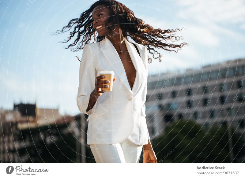 Elegant ethnic businesswoman walking in downtown with cup of coffee street trip style city cheerful tourist architecture vacation travel weekend female