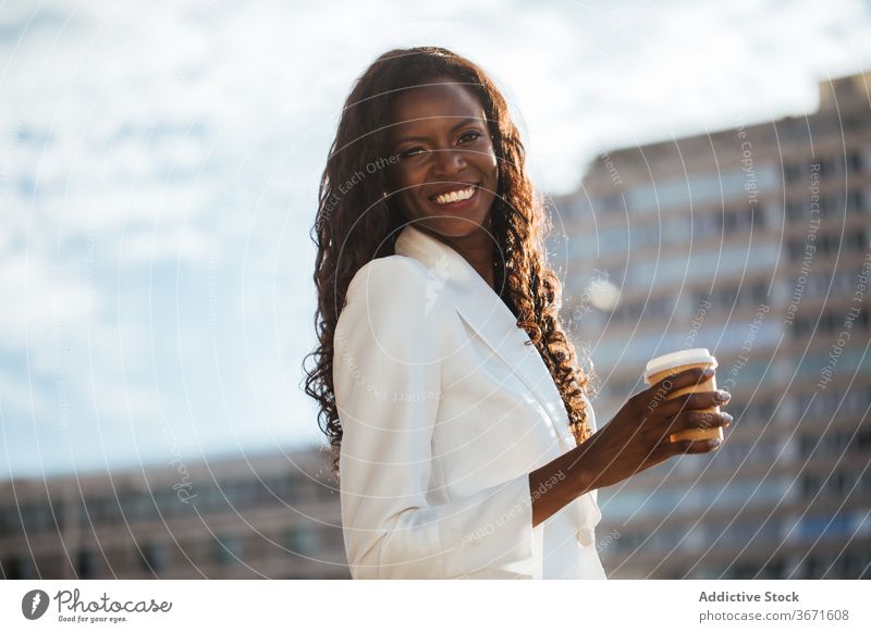 Elegant ethnic businesswoman walking in downtown with cup of coffee street trip style city cheerful tourist architecture vacation travel weekend female