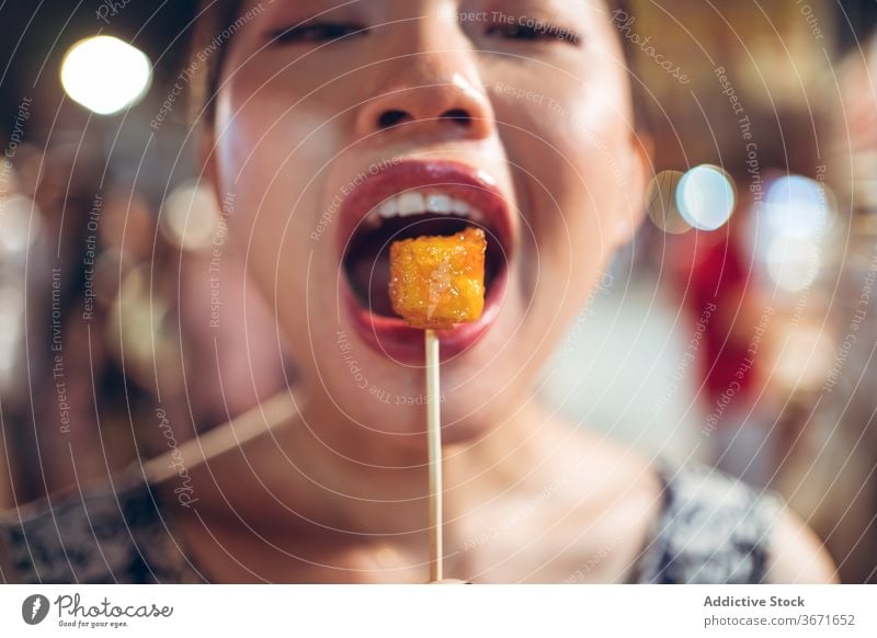 Smiling ethnic woman with sweet potato on street street food night market eat sugar coat zhubei night market female asian taiwan stick tasty yummy smile joy