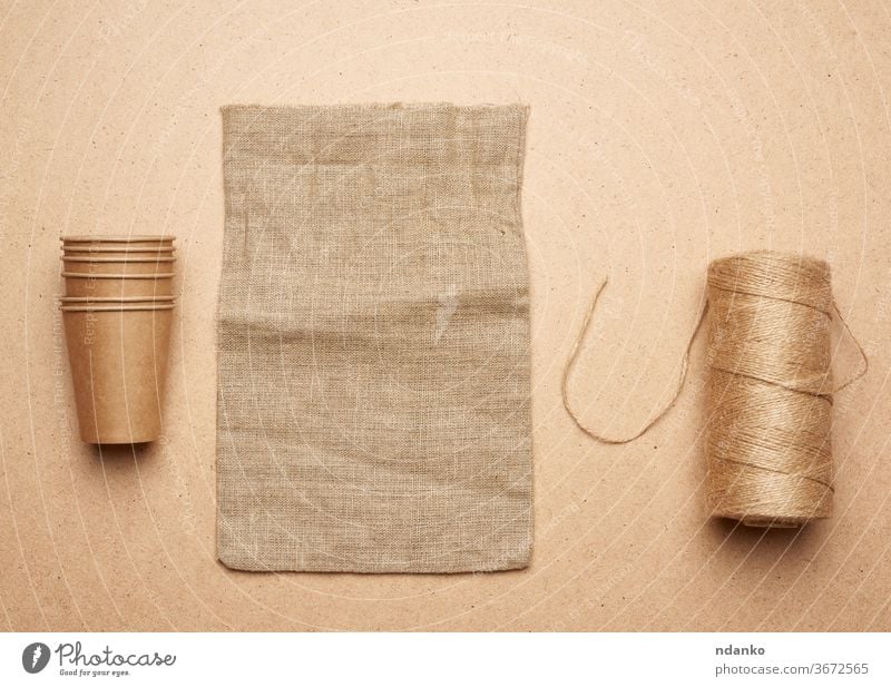 paper cup, skein with brown rope and empty bag on a brown wooden background concept accessory backdrop beige blank burlap canvas closeup cloth container design