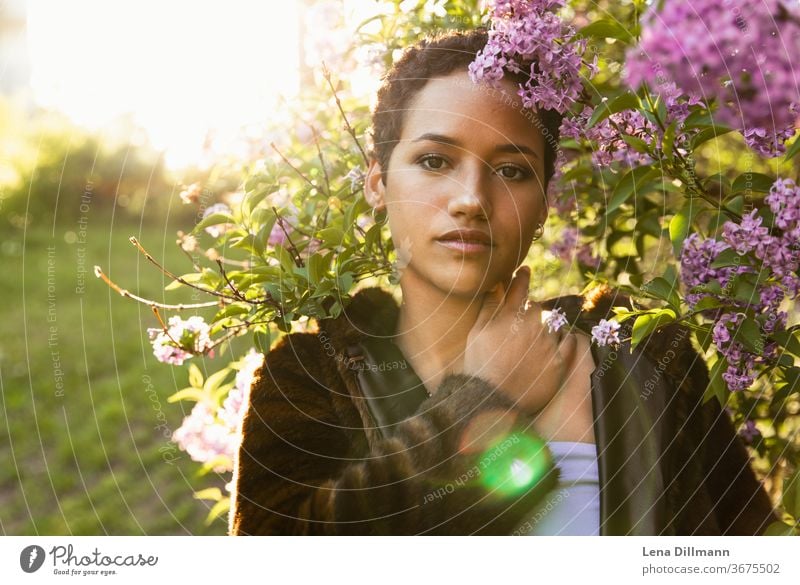 Woman in front of lilac tree #2 Young woman girl Teenage Girls teenager out Nature Lilac Tree shrub Lilac bush Sun sunny Sunlight Mixed Afro-German Curl Coat