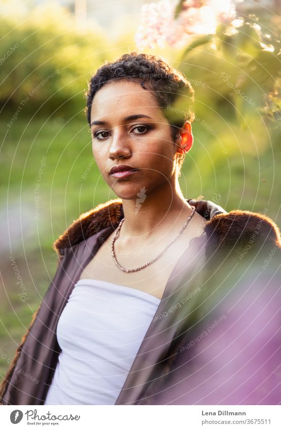 Woman in front of lilac tree #1 Young woman girl Teenage Girls teenager out Nature Lilac Tree shrub Lilac bush Sun sunny Sunlight Mixed Afro-German Curl Coat