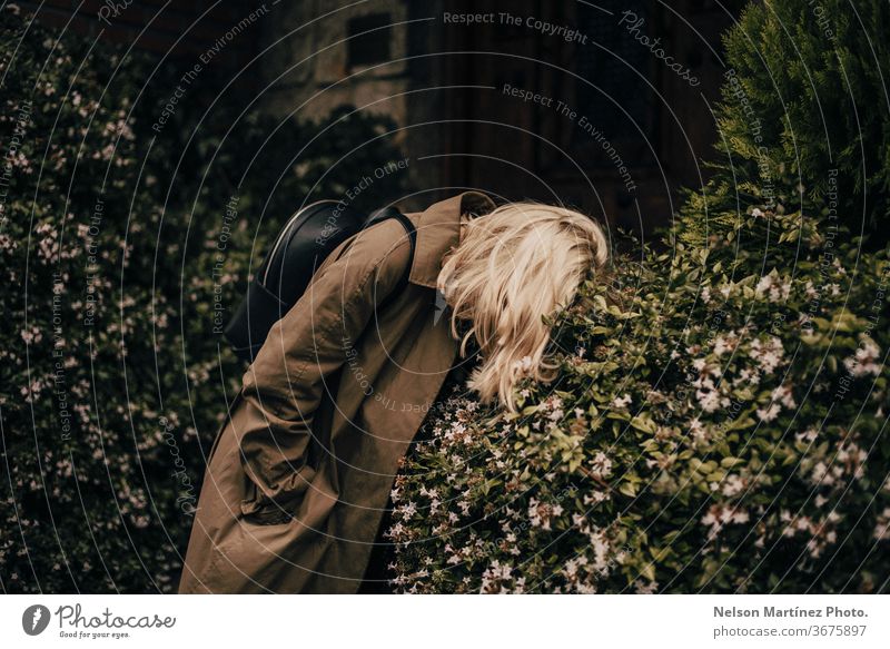 Portrait of a beautiful stylish blonde. She is wearing a green coat. She is bended in the bush. resting fashion lost frustrated no idea moody portrait woman