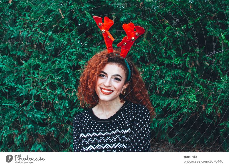 Young happy redhead woman near a christmas tree on holidays gift people real pretty young youth happiness merry christmas decor decoration hairband horns