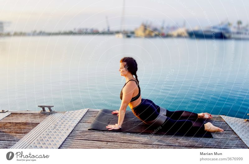 CHICA HACIENDO ESTIRAMIENTO DE ESPALDA DEPORTE SALUD AGUA MAR PUERTO BONITO VISTAS AMANECER AIRELIBRE VIDASANA estirar