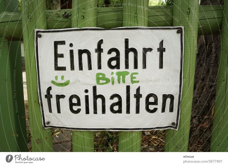 "Please keep driveway clear" is written on a dented metal sign on a green wooden fence keep the driveway clear please wish Fence Wooden fence Smiley