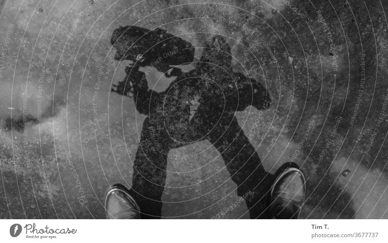 Girl with guitar Puddle reflection puddle mirroring Reflection Water Exterior shot Wet Asphalt Day Guitar Musician Gray girl Woman Footwear Black & white photo