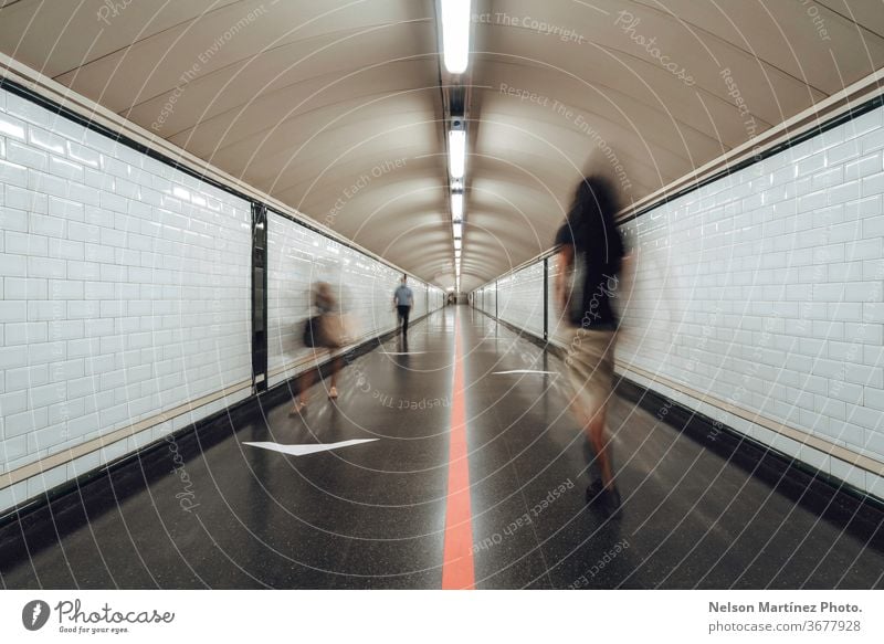 Blurred people walking in a large tunnel of a train station. The New Normal. A group of people rushing through a subway corridor. motion blur city railway