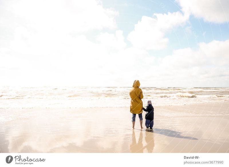 Mother and child on the beach Single parent at the same time Attachment Mother with child in common vacation Beach Parents Family Sunlight Rear view two persons