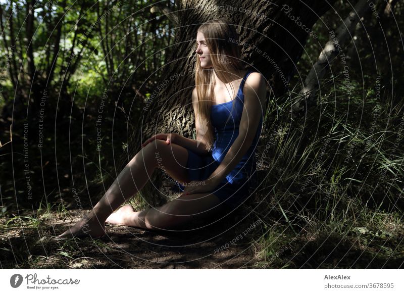 Portrait of a young woman in a blue summer dress in front of a tree with shadow play Purity luck Beautiful weather Trip Expectation Sunlight Close-up Day