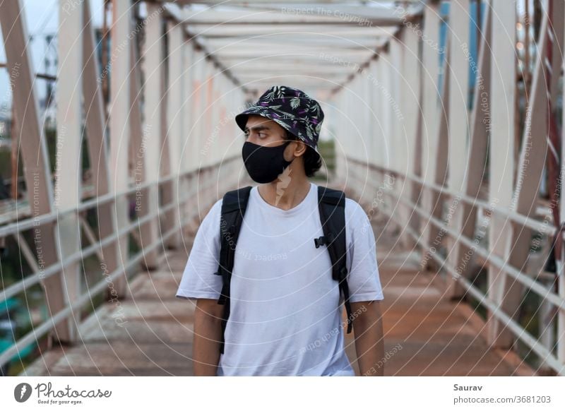 Portrait of a Young Millennial on a Foot Bridge Outdoors Wearing a Black Protective Face Mask to Prevent Covid-19 Virus Infection in a City. The New Normal.