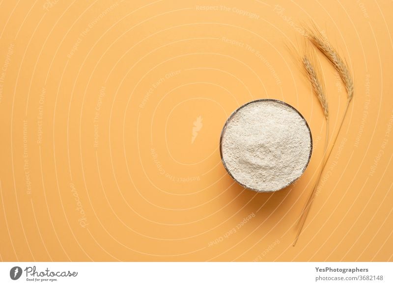 Wholemeal flour in a bowl isolated on a beige background. Bowl of flour top view above view bakery baking banner cereal cooking copy space cream creative layout