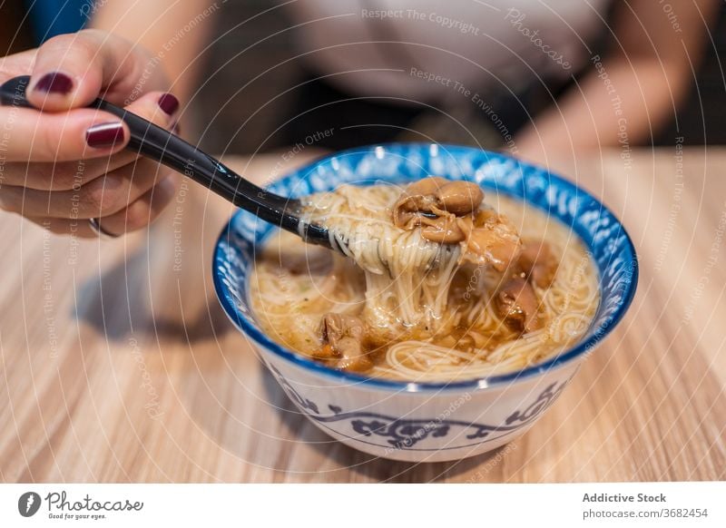 Asian woman eating traditional noodles soup taiwan asian food bowl young meal female ethnic lunch tasty dish lifestyle cuisine yummy hot blow oriental enjoy