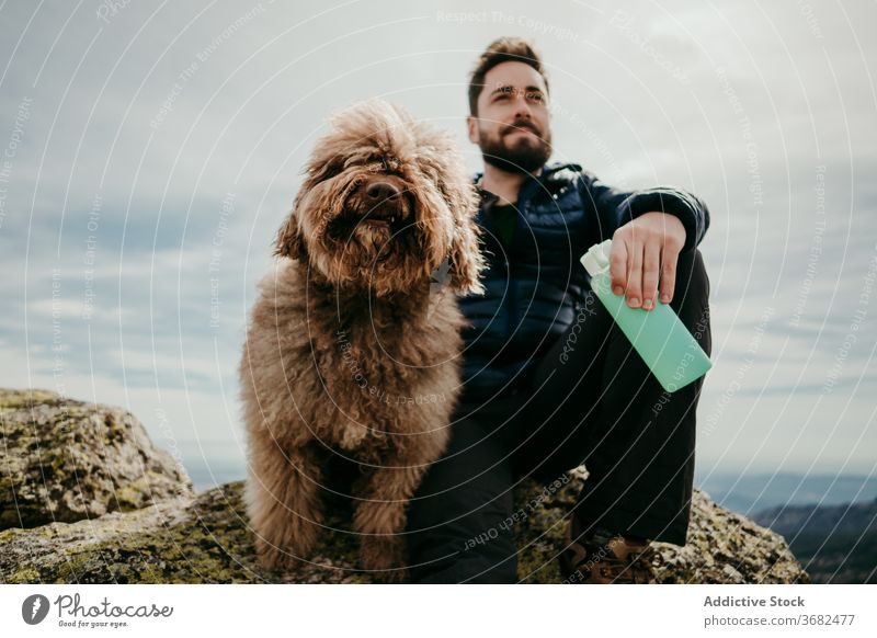 Male hiker with dog in mountains man rest trip sky overcast bottle puerto de la morcuera spain male water stone labradoodle cute journey nature sit rock