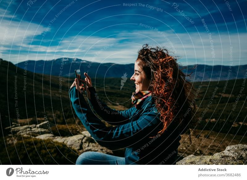 Positive female hiker shooting mountains woman smartphone take photo trip countryside smile ridge puerto de la morcuera spain cloudy sky device gadget relax