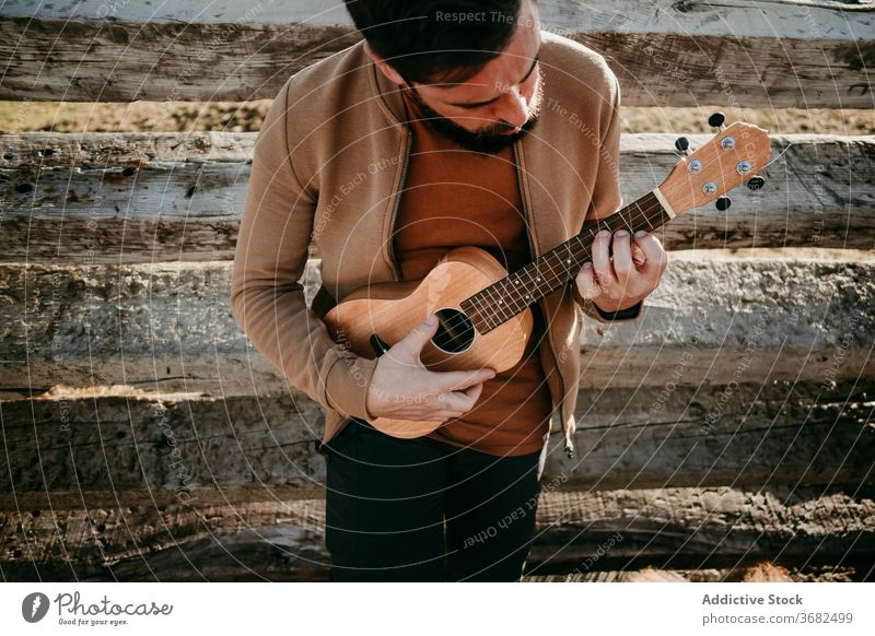 Male traveler resting near fence man mountain lean sunny daytime puerto de la morcuera spain male countryside wooden ukulele barrier relax nature journey trip