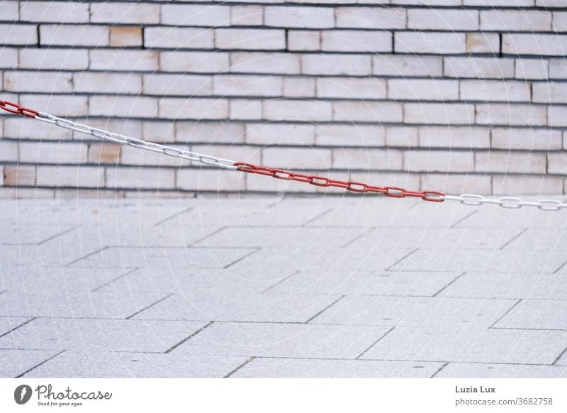 red and white chain barrier in front of light masonry Sidewalk Shut-off chain Street Traffic infrastructure Cobblestones Paving stone Stone Lanes & trails