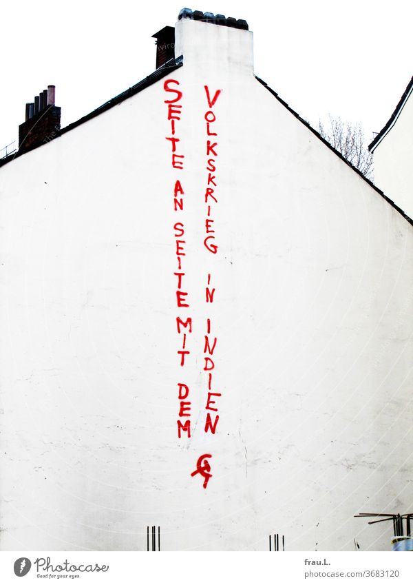 A vertically sprayed call for solidarity with the Naxalites is pinned to a white house facade. Maoists Poverty Peasant uprisings Guerilla fight Parties Adivasis