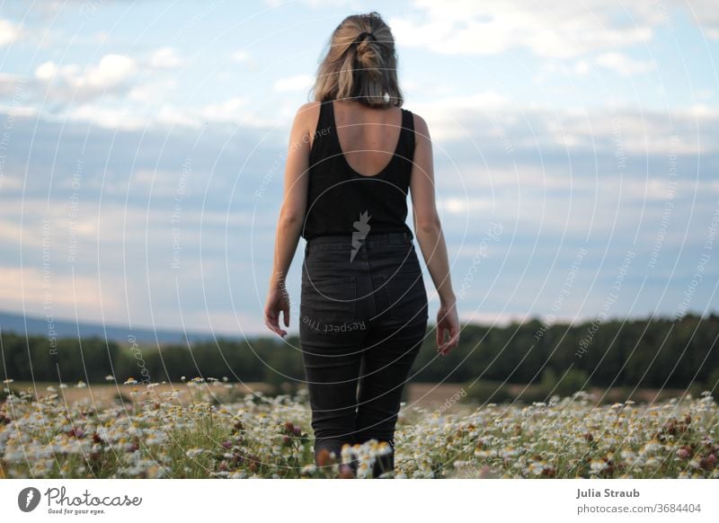 Young woman in jeans walks across a camomile field with a wonderful view Woman Jeans Black weaker Card Lanes & trails Sky Clouds Horizon Landscape Nature