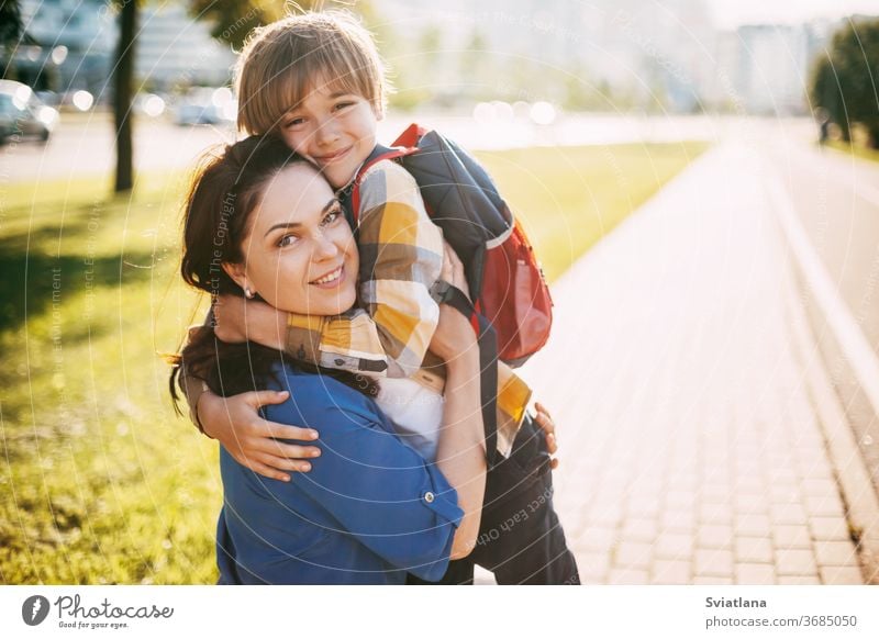 A mother hugs her young son on the way to school, and a mother and boy say goodbye before school. Concept of education and training, return to school back mom