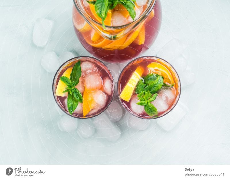 Fresh red coktail sangria in pitcher and glasses cocktail mocktail drink wine citrus orange above top view lemonade fruit summer decor leaf juice beverage mint