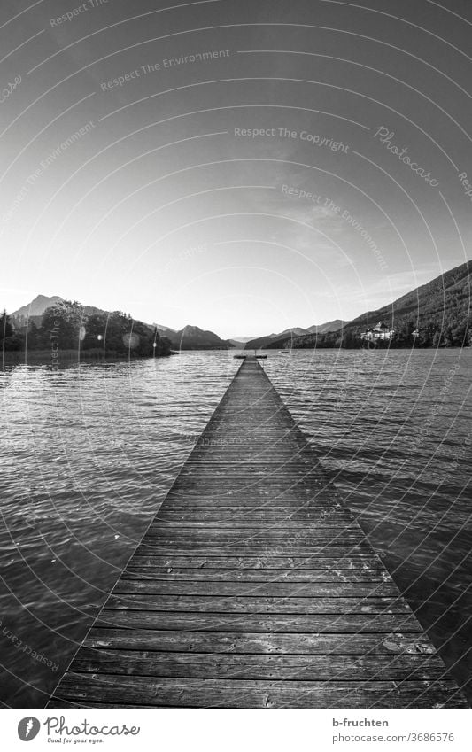 The path leads into the water, long wooden jetty at a mountain lake Footbridge off wooden walkway Fuschlsee Austria Salzkammergut Morning Nature Landscape