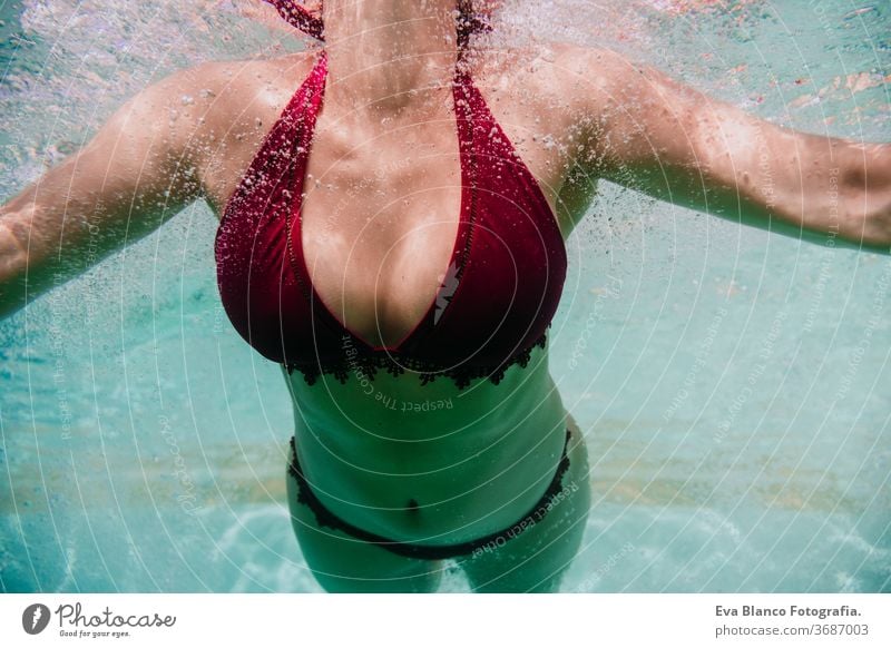 close up view of young woman diving underwater in a pool. summer and fun lifestyle swimming bubbles caucasian dive clear health light action wet swimmer blue