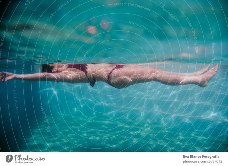 young woman floating in a pool. summer and fun lifestyle underwater swimming bubbles caucasian dive clear health light action wet swimmer blue active person