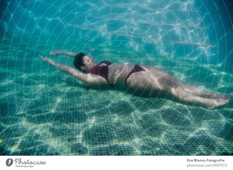 young woman floating in a pool. summer and fun lifestyle underwater swimming bubbles caucasian dive clear health light action wet swimmer blue active person