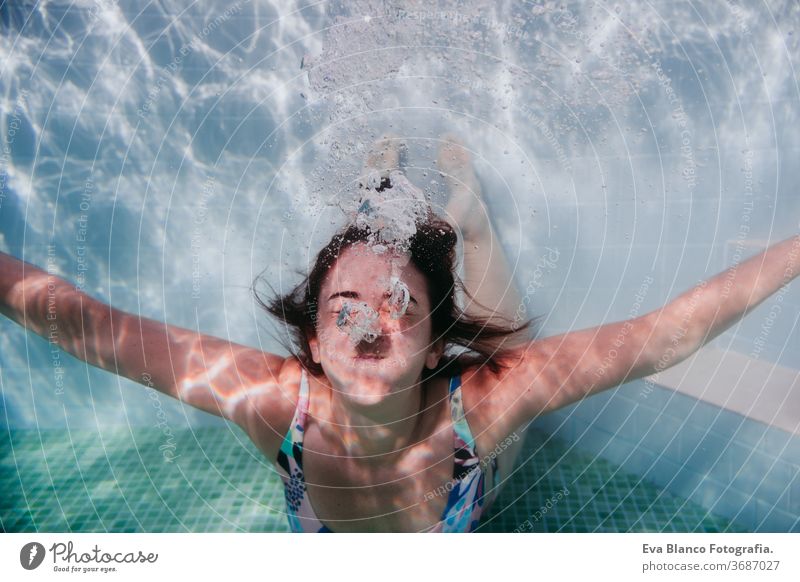 portrait of young woman diving underwater in a pool. summer and fun lifestyle close up swimming bubbles caucasian dive clear health light action wet swimmer