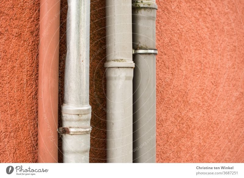 down pipes in front of an orange plastered wall, one orange and three grey Downspout Facade House (Residential Structure) Wall (building) Plastered Orange