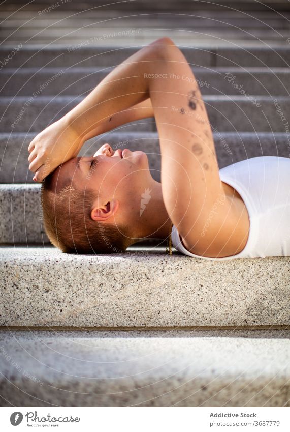 Young female lying on stairs woman step modern city street urban shaved subculture individuality young cover face summer rest town exterior model building