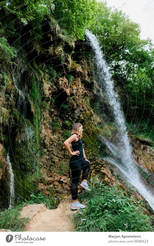 Young female nature explorer standing by the waterfall achievement active adult adventure awe cascade caucasian destination enjoying enjoyment environment