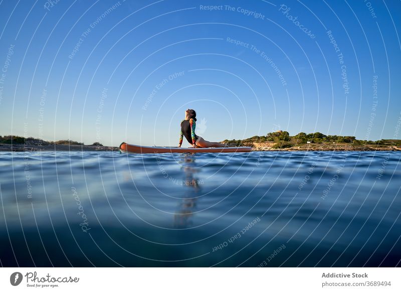 Flexible woman doing yoga on paddleboard sunset pose surfer balance sea female water healthy nature harmony relax tranquil serene sky calm ocean peaceful lady