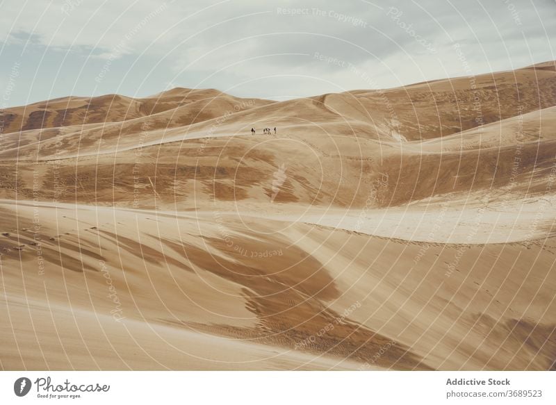 Travelers on sandy dunes on cloudy day tourist group national park desert landmark tourism colorado usa united states america vacation walk travel landscape