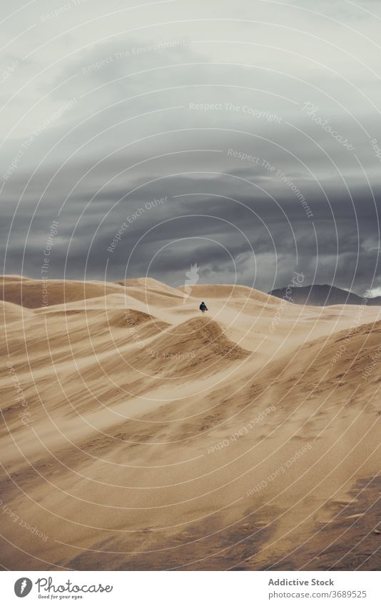 Anonymous traveler on sandy dunes on cloudy day tourist national park desert landmark tourism colorado usa united states america vacation walk person landscape