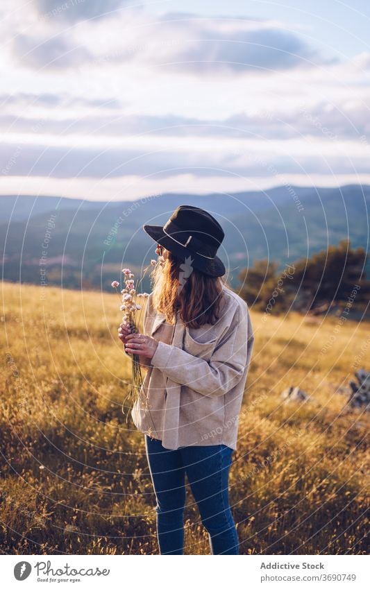 Carefree woman with flowers on hill tender bouquet wildflower mountain sunset blossom highland female sundown majestic landscape autumn dusk tranquil calm