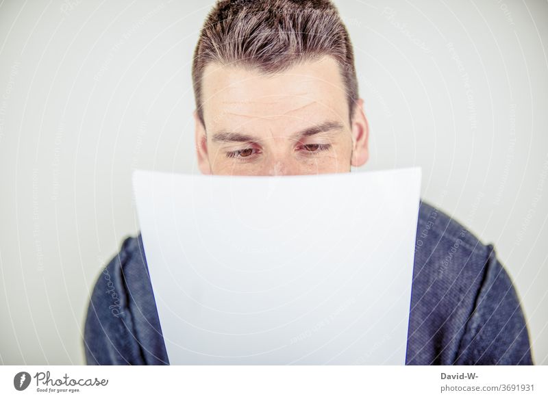 young man reads a piece of paper Piece of paper message Reading Young man Man adult read up Mail Letter (Mail) Message Paper Communicate Information Human being