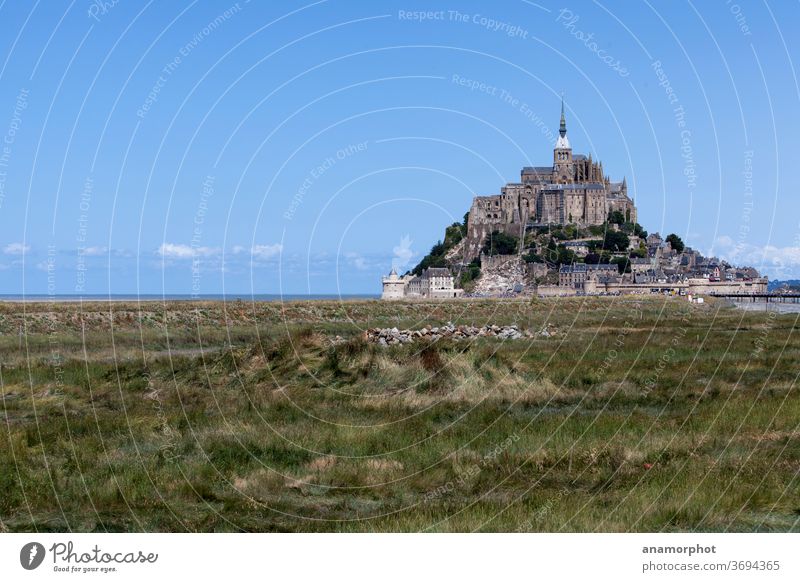 Rolls of straw on a field, Mont St. Michel in the background France Brittany Summer Sun Grain harvest Blue sky green beautiful day vacation voyage holidays